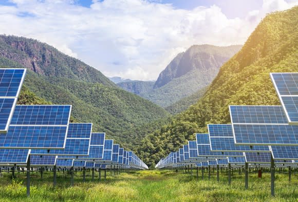 Solar array with a lush mountain in the background.