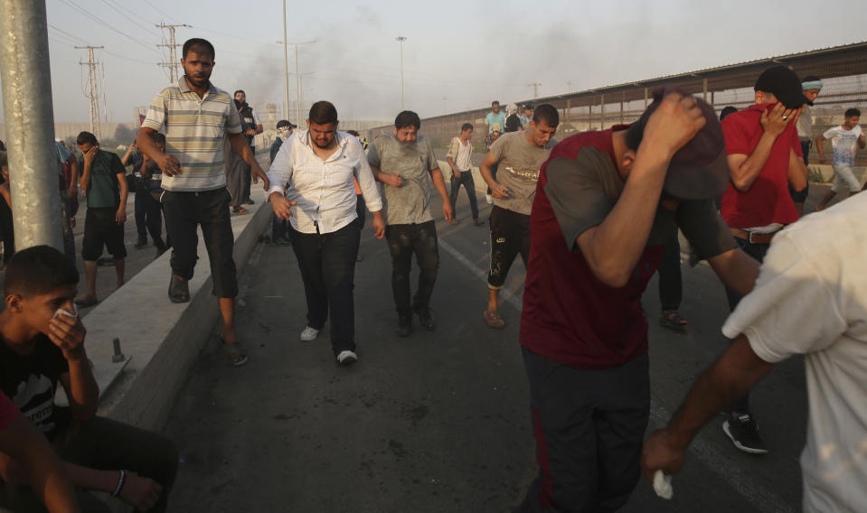 Protesters run to cover from teargas fired by Israeli soldiers during a protest at the entrance of Erez border crossing between Gaza and Israel, in the northern Gaza Strip, Tuesday, Sept. 4, 2018. The Health Ministry in Gaza says several Palestinians were wounded by Israeli fire as they protested near the territory's main personnel crossing with Israel. (AP Photo/Adel Hana)