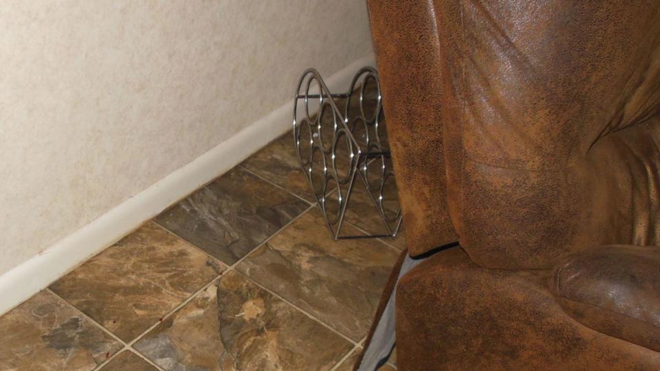 Steve Ducote and Betsy Jeansonne believe several of the photos show signs of a struggle, like this wine rack seemingly out of place behind a chair.   / Credit: Evidence photo