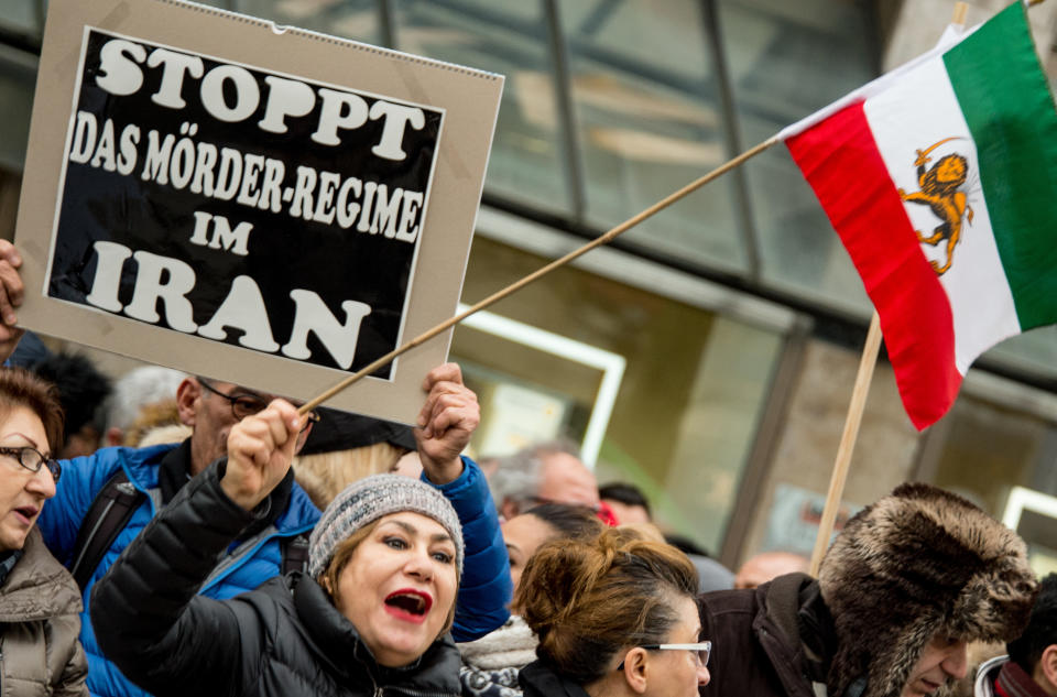 <p>A man carries a banner reading ‘Stop the Iranian murder regime’ at the same time as people wave the Flag of Iran (1907·1979) in Hamburg, Germany, Jan. 6,2018. (Photo: Axel Heimken/DPA via ZUMA Press) </p>