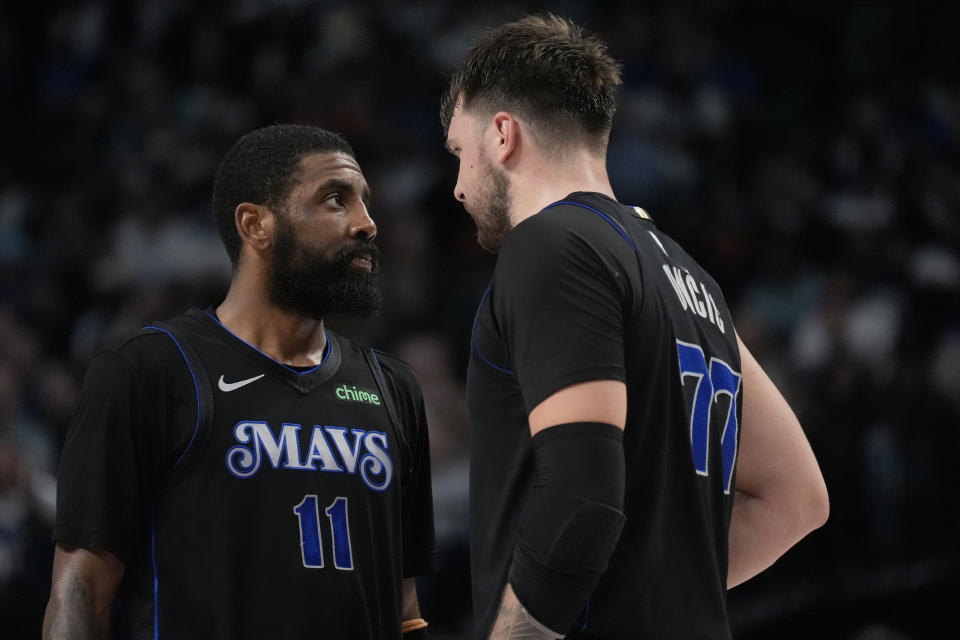 Dallas Mavericks' Kyrie Irving (11) and Luka Doncic (77) talk at midcourt during the second half of an NBA basketball game against the Phoenix Suns in Dallas, Thursday, Feb. 22, 2024. (AP Photo/Tony Gutierrez)