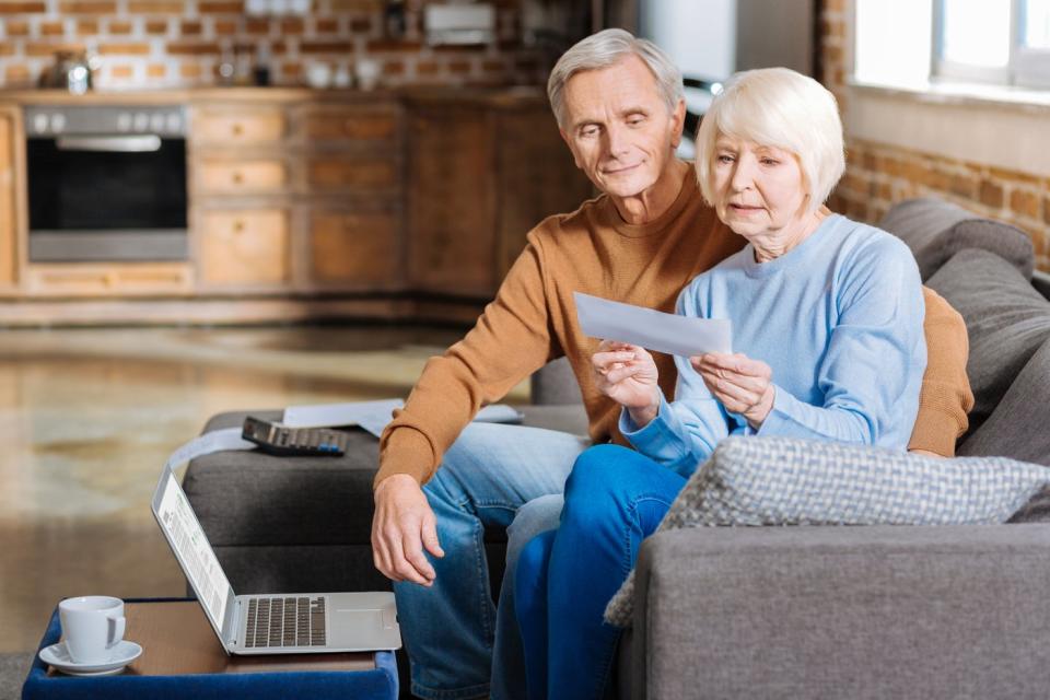 Two people sitting on couch looking at check.