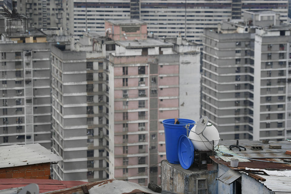 A man cleans the inside of a water container situated on the roof of his home in the San Agustin neighborhood of Caracas, Venezuela, Sunday, May 17, 2020. Water shortages have continued to deepen in Venezuela at a time when the threat of the coronavirus makes washing hands even more critical. (AP Photo/Matias Delacroix)