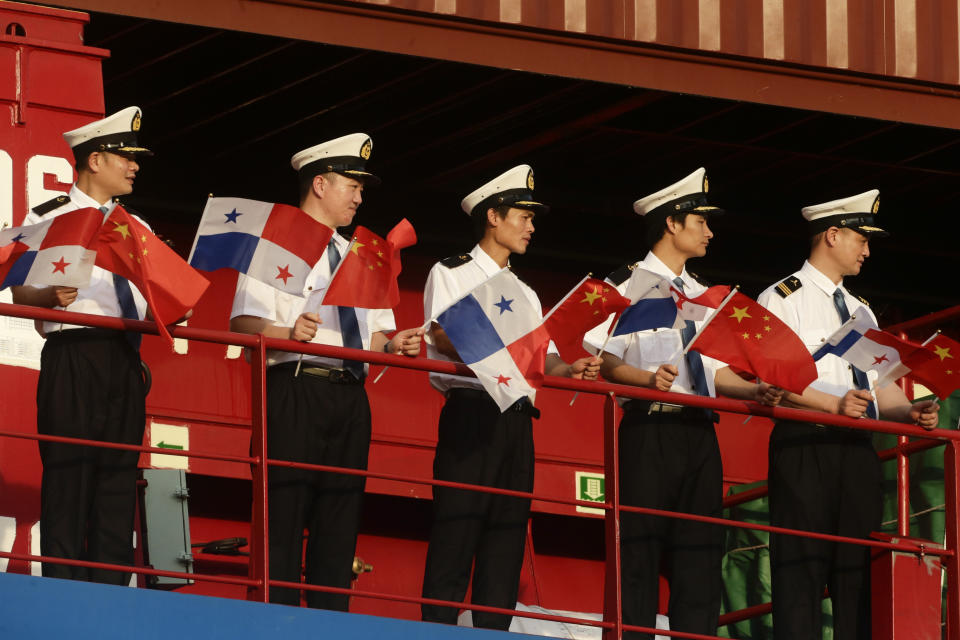 FILE - In this Dec. 3, 2018, file photo, sailors on the Chinese flagged ship "Cosco Shipping Rose" hold Panamanian and Chinese flags during a visit by China's President Xi Jinping and his wife first lady Peng Liyuan, at Cocoli Locks inside the Panama Canal in Panama City. China’s expansion in Latin America of its Belt and Road initiative to build ports and other trade-related facilities is stirring anxiety in Washington. As American officials express alarm at Beijing’s ambitions in a U.S.-dominated region, China has launched a charm offensive, wooing Panamanian politicians, professionals, and journalists. (AP Photo/Arnulfo Franco, File)