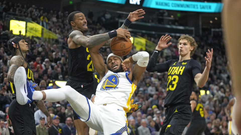 Utah Jazz forward John Collins, center left, defends against Golden State Warriors guard Moses Moody (4) during the second half of an NBA basketball game Monday, Feb. 12, 2024, in Salt Lake City. (AP Photo/Rick Bowmer)