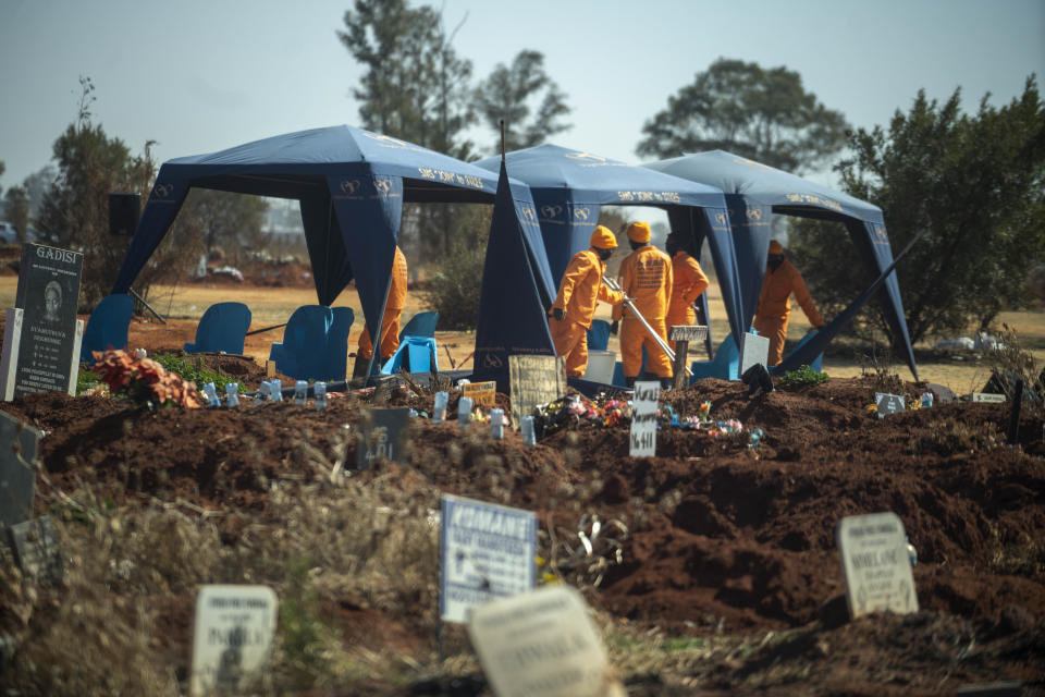 Workers prepare for a burial at the Olifantsveil Cemetery outside Johannesburg, South Africa, Thursday Aug. 6, 2020. The frequency of burials in South Africa has significantly increased during the coronavirus pandemic, as the country became one of the top five worst-hit nations. New infection numbers around the world are a reminder that a return to normal life is still far off. (AP Photo/Jerome Delay)