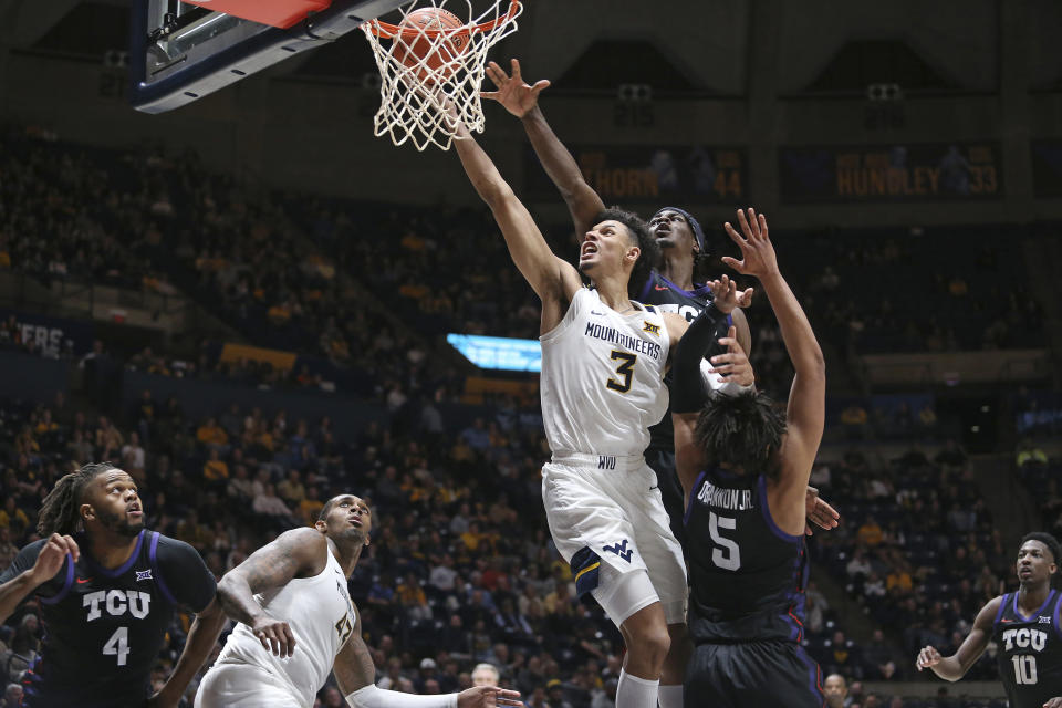 West Virginia forward Tre Mitchell (3) is defended by TCU forwards Emanuel Miller, behind, and Chuck O'Bannon Jr. (5) during the second half of an NCAA college basketball game Wednesday, Jan. 18, 2023, in Morgantown, W.Va. (AP Photo/Kathleen Batten)