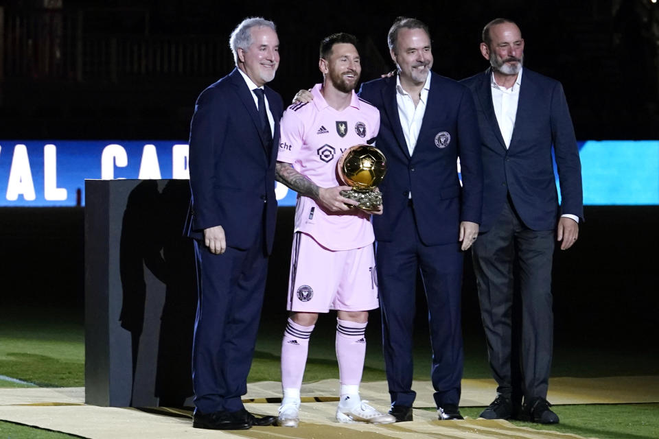 Inter Miami forward Lionel Messi, second form left, holds his Ballon d'Or trophy before the team's club friendly soccer match against New York City FC, Friday, Nov. 10, 2023, in Fort Lauderdale, Fla. Also pictured are Inter Miami managing owner Jorge Mas, left, Inter Miami co-owner Jose Mas, second from right, and MLS Commissioner Don Garber. (AP Photo/Lynne Sladky)
