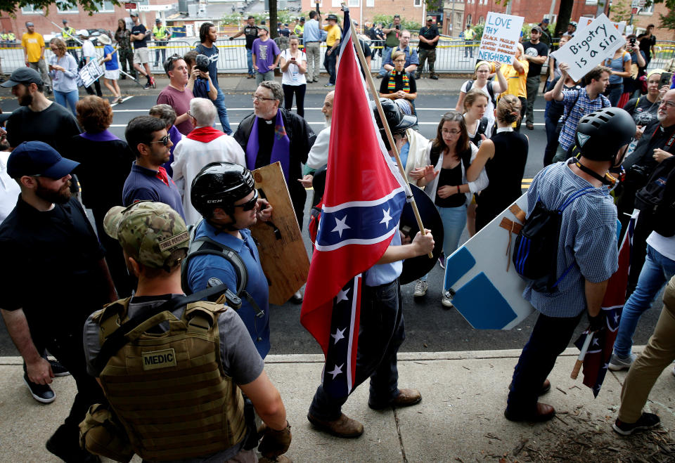 A white supremacist carries the Confederate flag as he walks past counter-demonstrators.