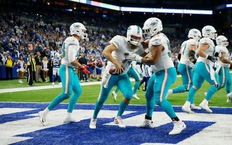 Miami Dolphins quarterback Ryan Fitzpatrick (14) is congratulated by teammates after scoring a touchdown against the Indianapolis Colts during the second quarter at Lucas Oil Stadium - Credit: USA Today