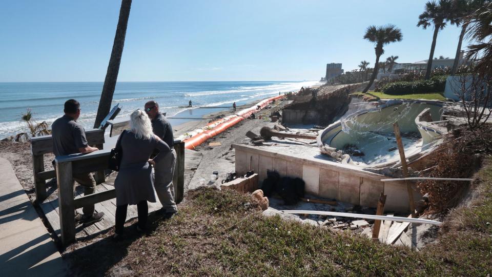 Florida Department of Emergency Management and Volusia County officials stand at the edge of eroded Frank Rendon Park in Daytona Beach Shores, right next to where construction crews are installing a Tiger Dam system, Tuesday, Nov. 29, 2022.