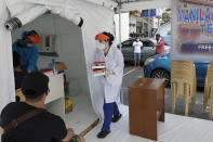 A health worker carries blood samples at a parking lot that has been converted into an extension of the Gat Andres Bonifacio Memorial Medical Center in Manila, Philippines on Monday, Aug. 3, 2020. Philippine President Rodrigo Duterte is reimposing a moderate lockdown in the capital and outlying provinces after medical groups appealed for the move as coronavirus infections surge alarmingly. (AP Photo/Aaron Favila)