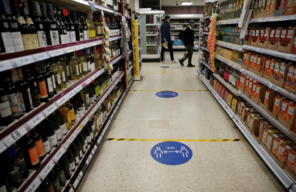 Floor stickers in the alcohol aisle inside a Tesco Metro supermarket ask customers to social distance as they shop, in London on September 23, 2020. - Britain on Tuesday tightened restrictions to stem a surge of coronavirus cases, ordering pubs to close early and advising people to go back to working from home to prevent a second national lockdown. (Photo by Hollie Adams / AFP) (Photo by HOLLIE ADAMS/AFP via Getty Images)