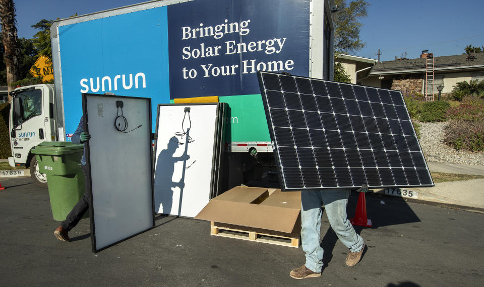 GRANADA HILLS, CA - JANUARY 04, 2020: Aaron Newsom, left, an installer for the solar company, Sunrun, and Tim McKibben, a senior installer, prepare solar panels to be installed on the roof of a home in Granada Hills.  (Mel Melcon / Los Angeles Times via Getty Images)