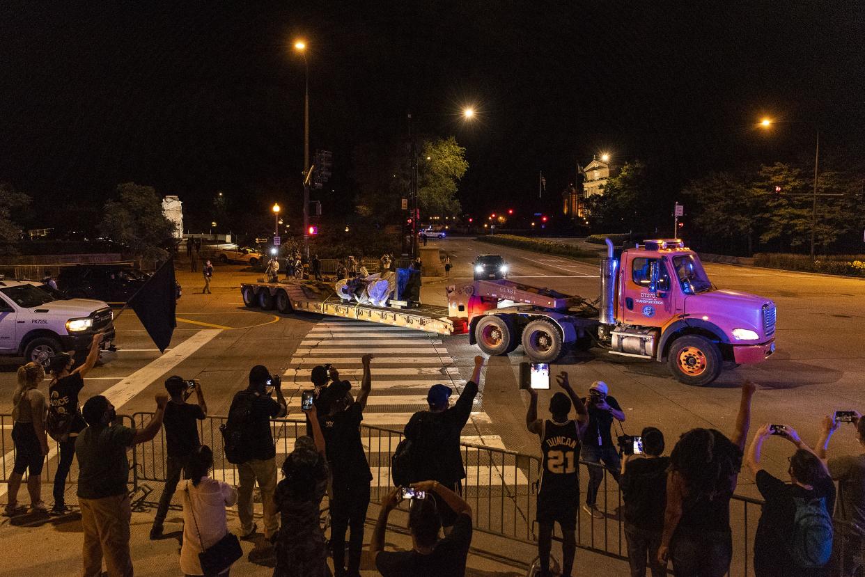 A group of people in support of the removal of a Christopher Columbus statue cheer as it is driven away from Grant Park on July 24, 2020 in Chicago.