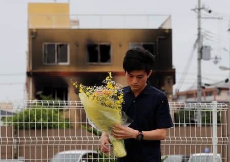 A man prays for victims in front of the torched Kyoto Animation building in Kyoto