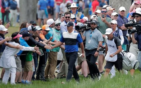 Brooks Koepka slaps the hands of a few spectators as he walks up the 2nd - Credit: AP