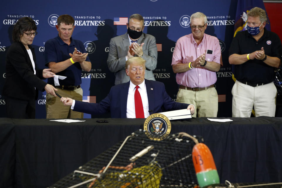 President Donald Trump hands pens out after signing an executive order on commercial fishing after speaking at a roundtable discussion with commercial fishermen at Bangor International Airport in Bangor, Maine, Friday, June 5, 2020. (AP Photo/Patrick Semansky)