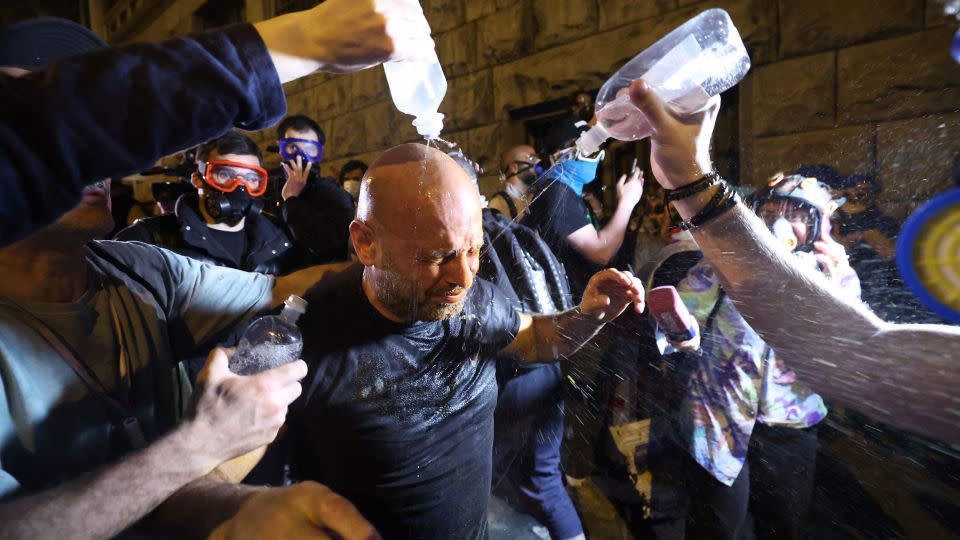 People try to wash away tear gas from the eyes of a protester, May 1, 2024. - Giorgi Arjevanidze/AFP/Getty Images