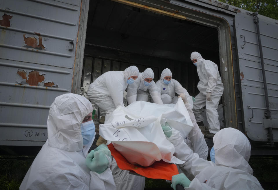 Militares ucranianos suben los cuerpos de soldados rusos a un vagón de ferrocarril refrigerado el viernes 13 de mayo de 2022 en Kiev, Ucrania. (AP Foto/Efrem Lukatsky)