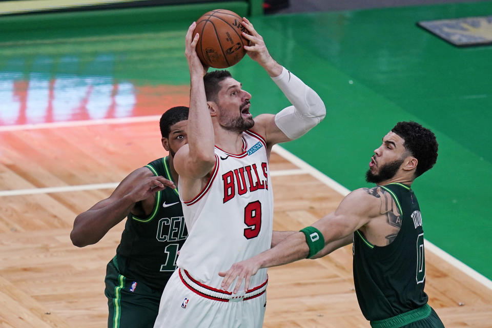 Chicago Bulls center Nikola Vucevic (9) shoots while pressured Boston Celtics forward Jayson Tatum, right, and center Tristan Thompson, rear, during the second half of an NBA basketball game, Monday, April 19, 2021, in Boston. (AP Photo/Charles Krupa)