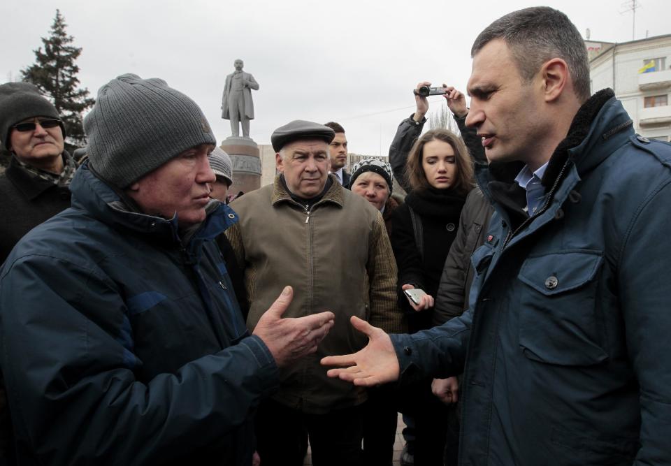 Ukrainian lawmaker and chairman of the Ukrainian party Udar (Punch), former WBC heavyweight boxing champion Vitali Klitschko, right, speaks with locals in Donetsk, Ukraine, Sunday, March 9, 2014. At background left is a statue of Soviet revolutionary leader Vladimir Lenin. (AP Photo/Sergei Chuzavkov)