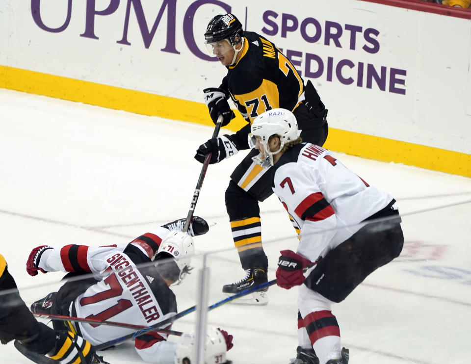 Pittsburgh Penguins' Evgeni Malkin, top, is penalized for tripping New Jersey Devils' Jonas Siegenthaler, lower left, during the first period of an NHL hockey game, Thursday, Feb. 24, 2022, in Pittsburgh. (AP Photo/Keith Srakocic)