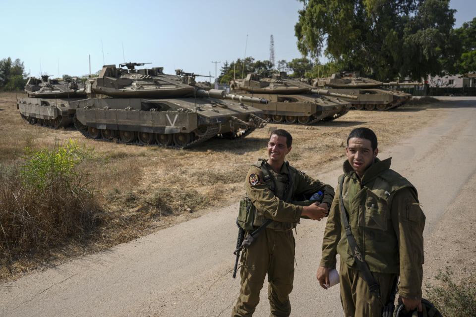 Israeli soldiers near their tanks in an area near the border with Gaza Strip, Friday, Aug. 5, 2022. Israel has closed roads near Gaza and sent in troop reinforcements as it braces for a possible revenge attack, following the arrest of a senior Palestinian militant in the occupied West Bank earlier this week. (AP Photo/Ariel Schalit)