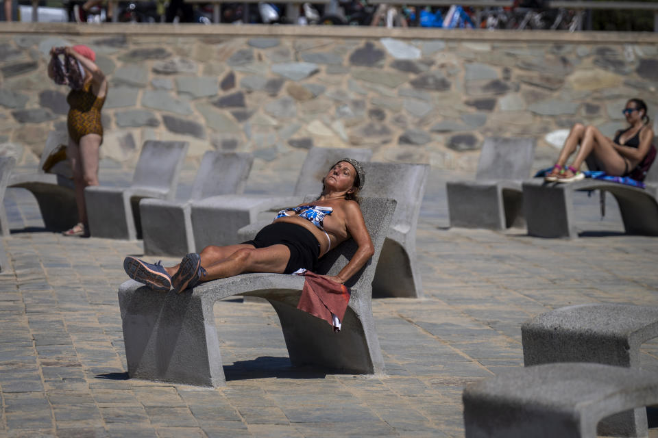 People sunbathe on a promenade in Barcelona, Spain, Wednesday, July 24, 2024. Several regions of Spain are under alert for high temperatures. (AP Photo/Emilio Morenatti)