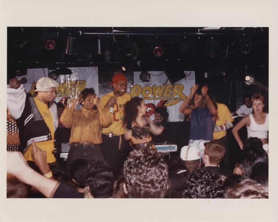 Brother Marquis from 2 Live Crew (left) performing at a show with fans dancing on stage. Luther “Uncle Luke” Campbell is in the center.