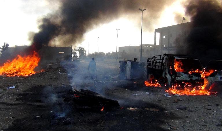 A man walks amidst smoke and fire following a string of Syrian regime air strikes on the Islamic State group's self-proclaimed capital of Raqa, on November 25, 2014