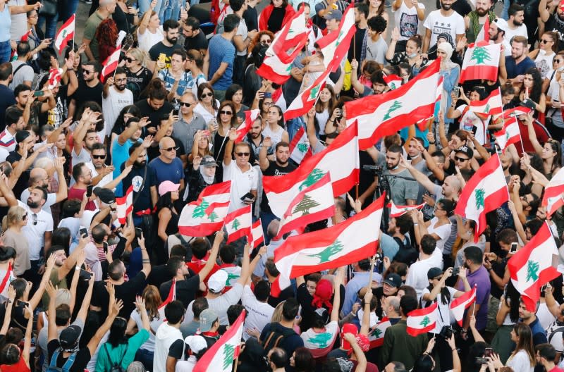 Demonstrators carry national flags and gesture during an anti-government protest in Beirut