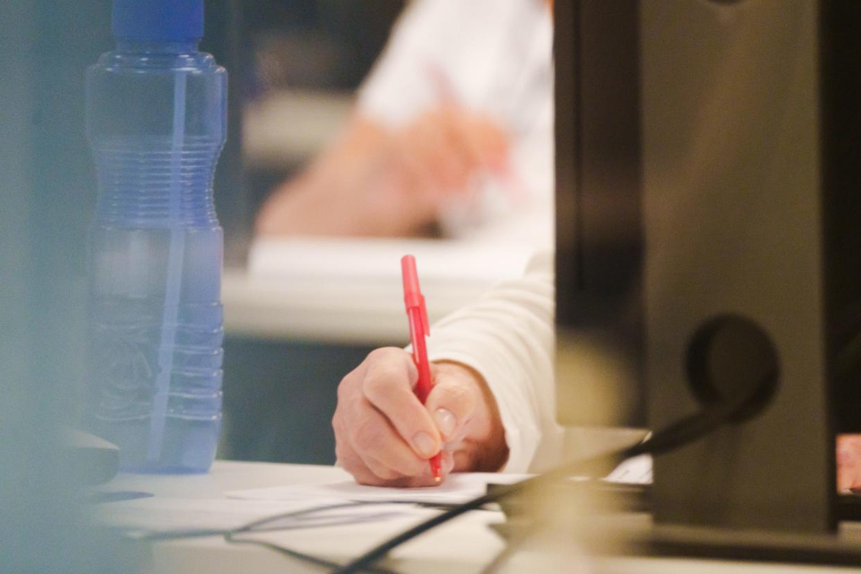 A bipartisan adjudicator writes with a red pen as early write-in votes and over-votes are reviewed at the Maricopa County Tabulation and Election Center on Aug. 1, 2022, in Phoenix, Ariz.