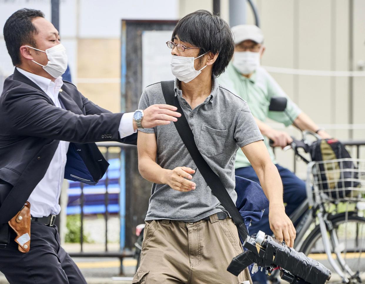 Tetsuya Yamagami, center, holding a homemade weapon, is detained near the site of gunshots in Nara, western Japan, on Friday.