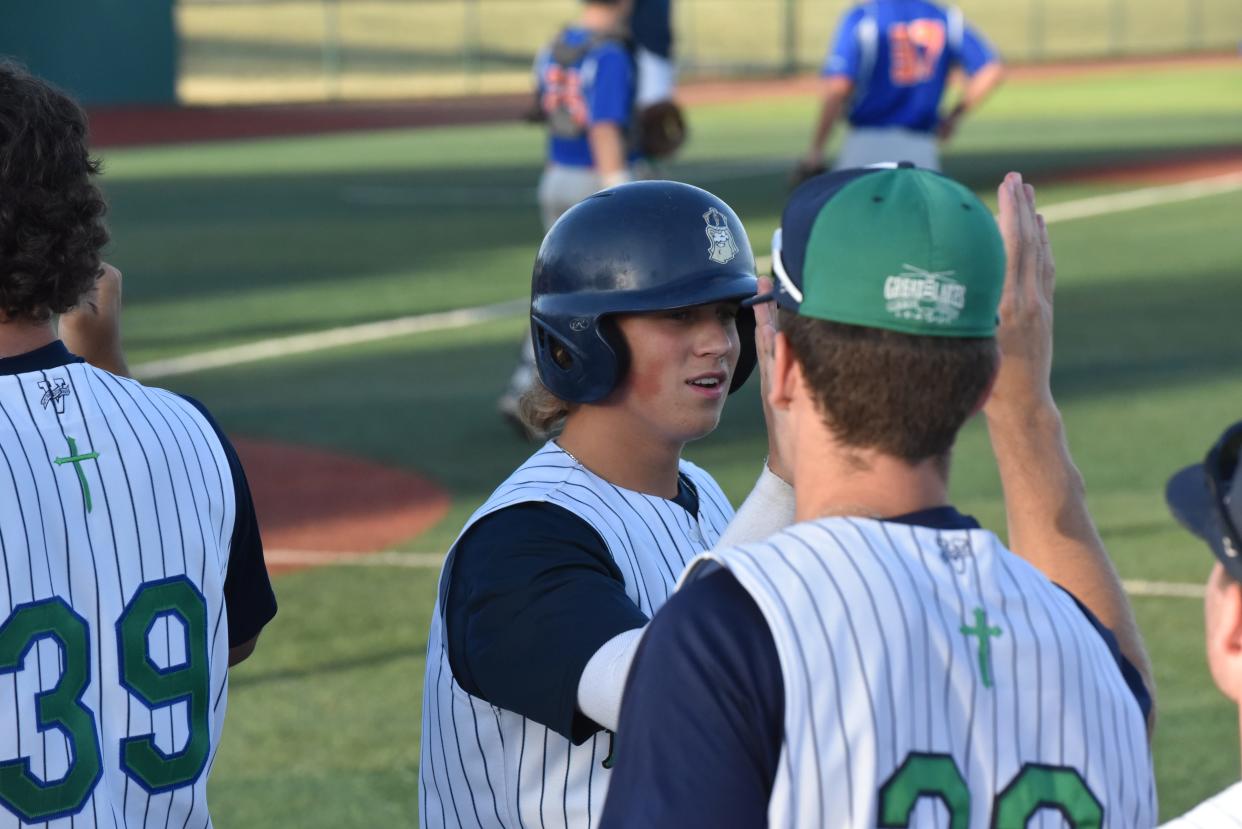 Camden Coleman is greeted outside of the dugout after scoring a run for the Michigan Monarchs during Thursday's GLSCL playoff game.