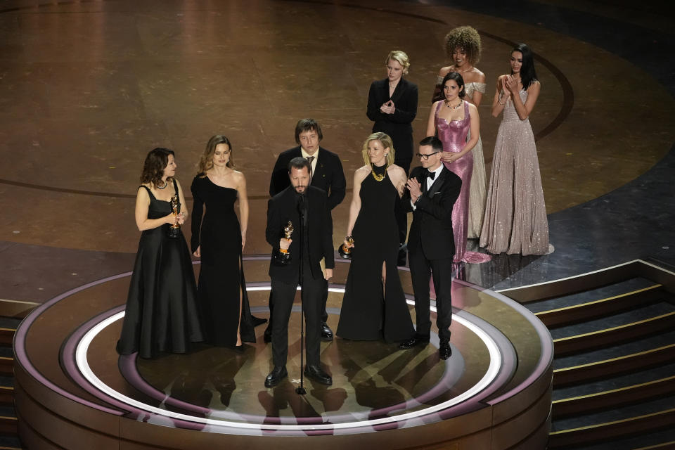 Raney Aronson-Rath, from left, Vasilisa Stepanenko, Mstyslav Chernov, Evgeniy Maloletka, Michelle Mizner, and Derl McCrudden accept the award for best documentary feature film for "20 Days in Mariupol" during the Oscars on Sunday, March 10, 2024, at the Dolby Theatre in Los Angeles. Kate McKinnon and America Ferrera look on from right.(AP Photo/Chris Pizzello)