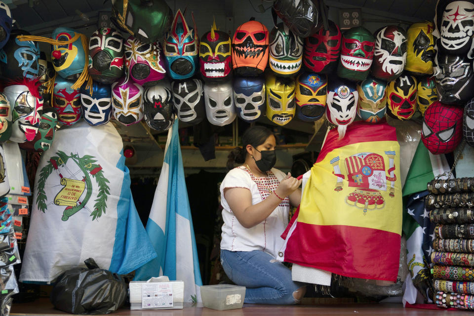 FILE - In this June 8, 2021, file photo, clerk Wendy Ramirez uses a Spanish flag to wrap souvenirs while preparing to close the store for the day on Olvera Street in Los Angeles. Los Angeles County residents are again required to wear masks indoors regardless of their vaccination status, a new mandate starting this weekend that health officials hope will reverse the latest spikes in coronavirus cases, hospitalizations and deaths. The rule went into effect late Saturday, July 17, for the nation's largest county, home to 11 million people, where a sharp increase in COVID-19 cases is led by the highly transmissible delta variant. (AP Photo/Jae C. Hong, File)