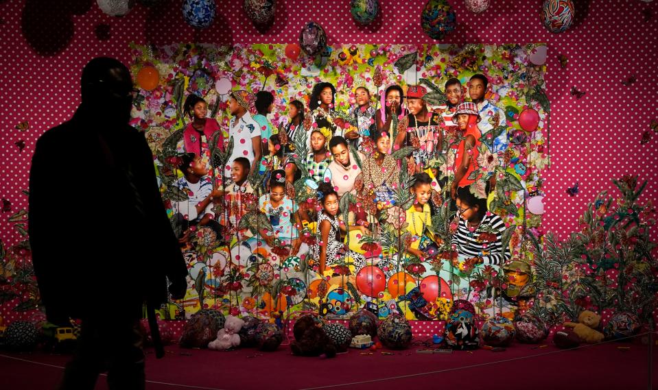 A person walks past Ebony G. Patterson's ". . . they were just hanging out you know . . . talking about . . . ( . . . when they grow up . . . )," during a press preview of the exhibition Giants Art from the Dean Collection of Swizz Beatz and Alicia Keys at the Brooklyn Museum in New York.