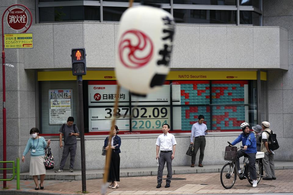 People stand in front of an electronic stock board showing Japan's Nikkei 225 index at a securities firm as a local festival lantern is placed nearby Tuesday, June 4, 2024, in Tokyo. (AP Photo/Eugene Hoshiko)