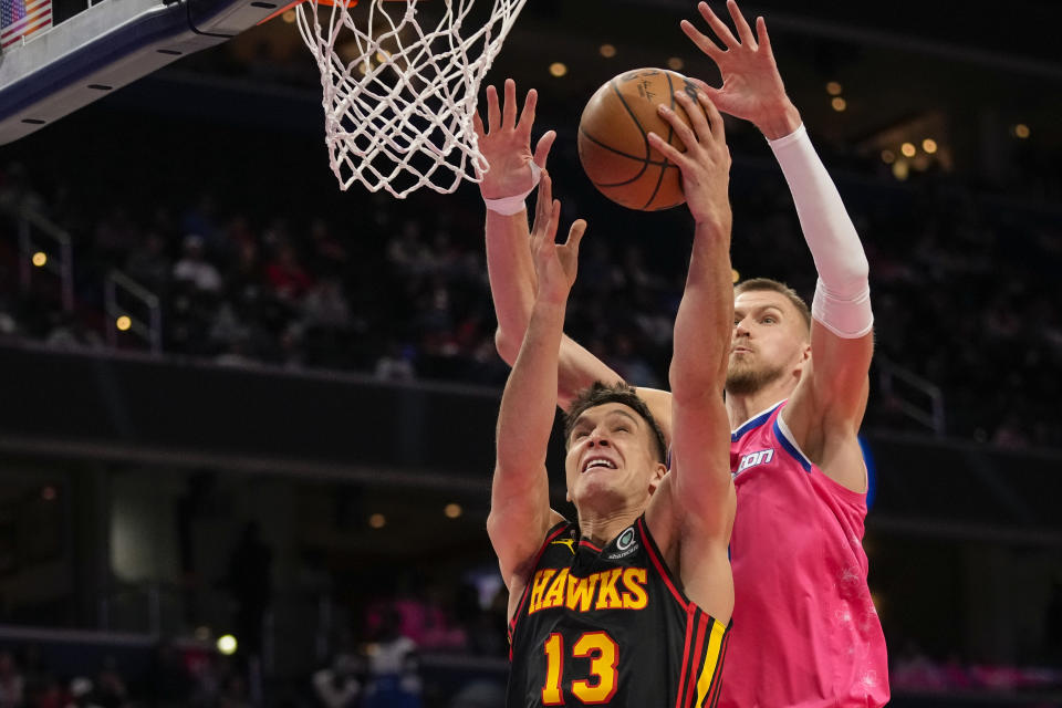 Atlanta Hawks guard Bogdan Bogdanovic (13) shoots in front of Washington Wizards center Kristaps Porzingis (6) during the second half of an NBA basketball game Wednesday, March 8, 2023, in Washington. The Hawks won 122-120. (AP Photo/Alex Brandon)