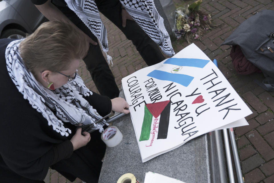 A pro-Palestinian activist works on a protest poster near the International Court of Justice, or World Court, in The Hague, Netherlands, Monday, April 8, 2024, prior to the start of a two days hearing in a case brought by Nicaragua accusing Germany of breaching the genocide convention by providing arms and support to Israel. (AP Photo/Patrick Post)