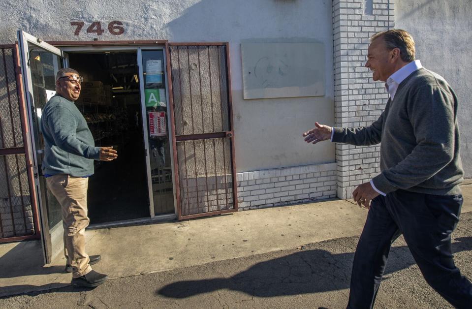 Mayoral candidate Rick Caruso greets business owner Sergio Pulido in front of Gust Picoulas Nut Company in downtown L.A.