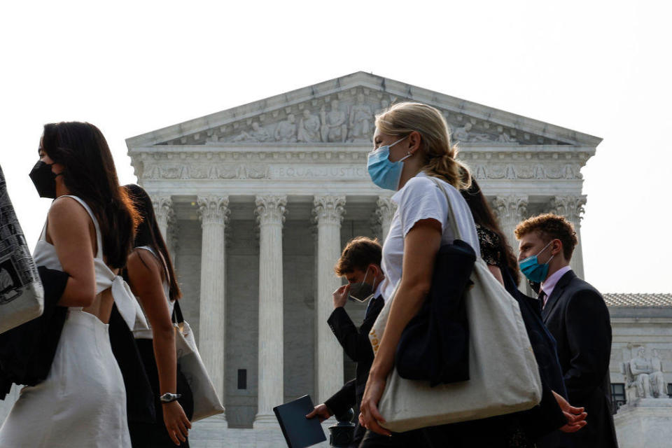 A group of people wear face masks to protect against air pollution as they walk past the Supreme Court Building on June 29, 2023, in Washington, D.C. / Credit: Anna Moneymaker/Getty Images