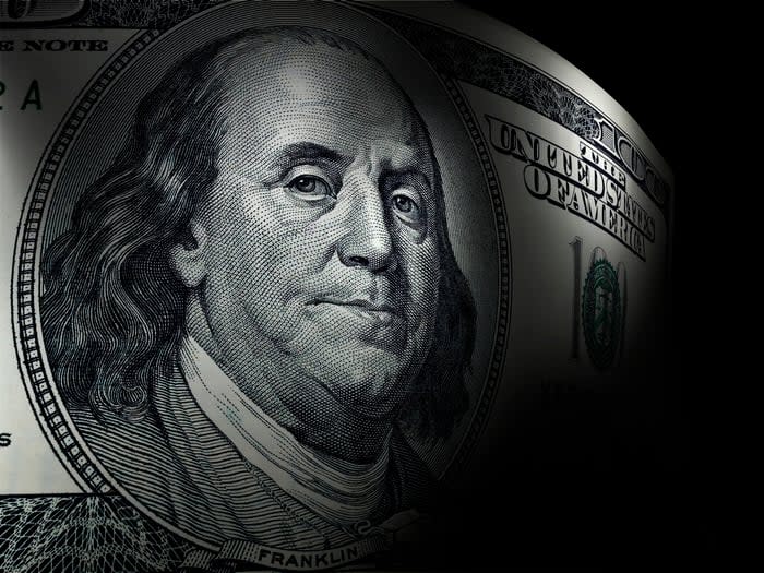 An up-close view of Ben Franklin's portrait on a one hundred dollar bill that's set against a dark background.