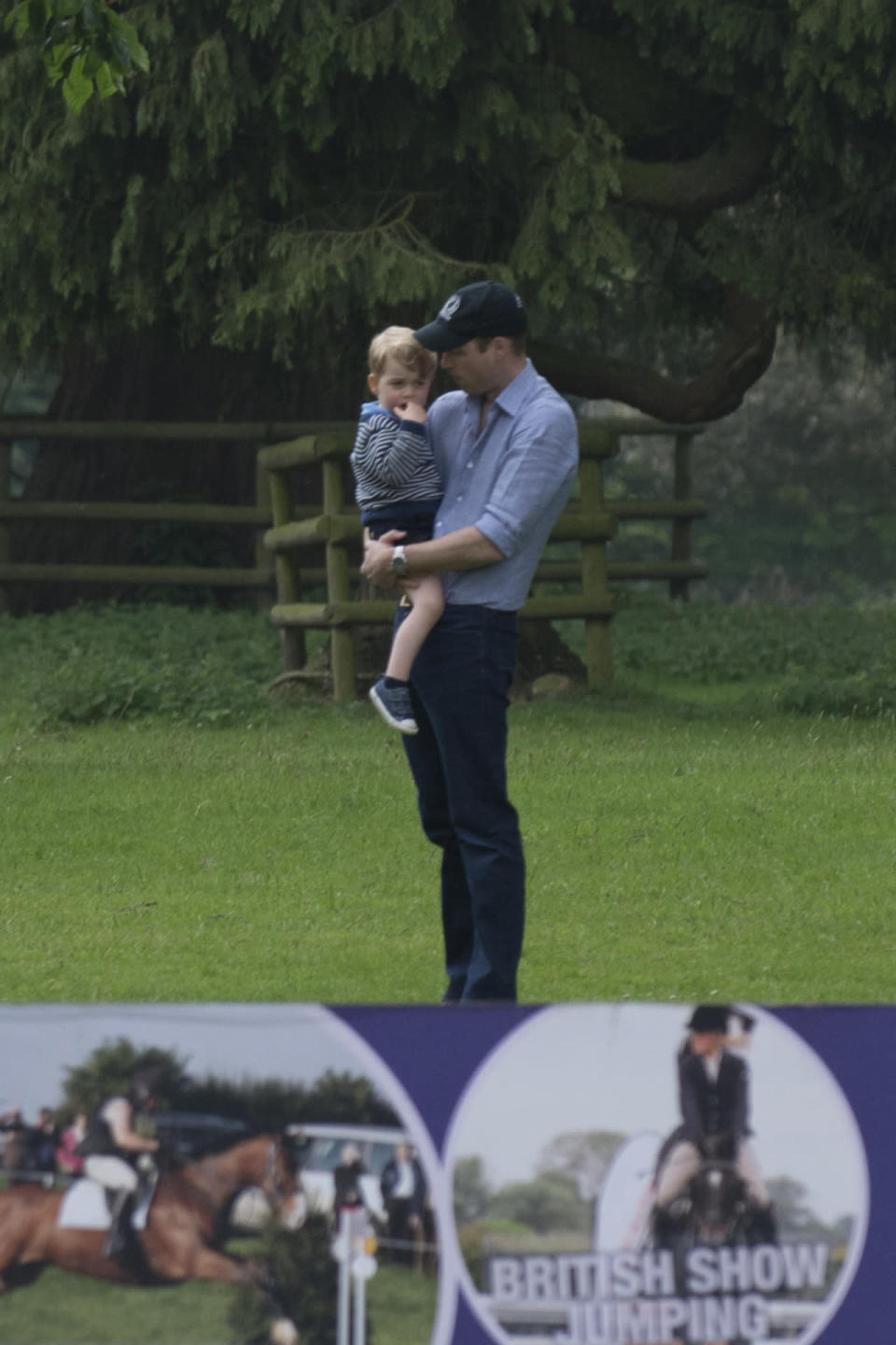 Prince William, decked out in a blue shirt, chinos and a baseball cap, was captured enjoying a tender moment with his son. 