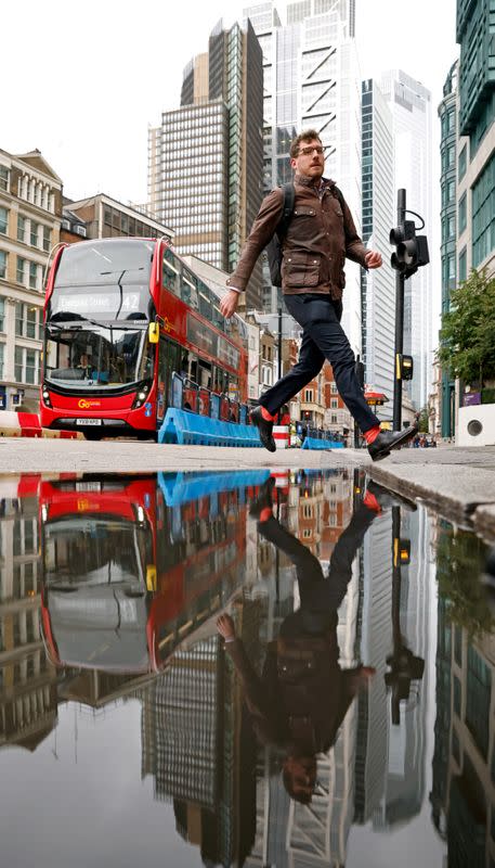 FILE PHOTO: A man jumps over a puddle in the City of London financial district during the morning rush hour