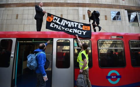 Climate activists on top of a Dockland Light Railway at Canary Wharf station in east London  - Credit: &nbsp;Kirsty O'Connor/PA&nbsp;