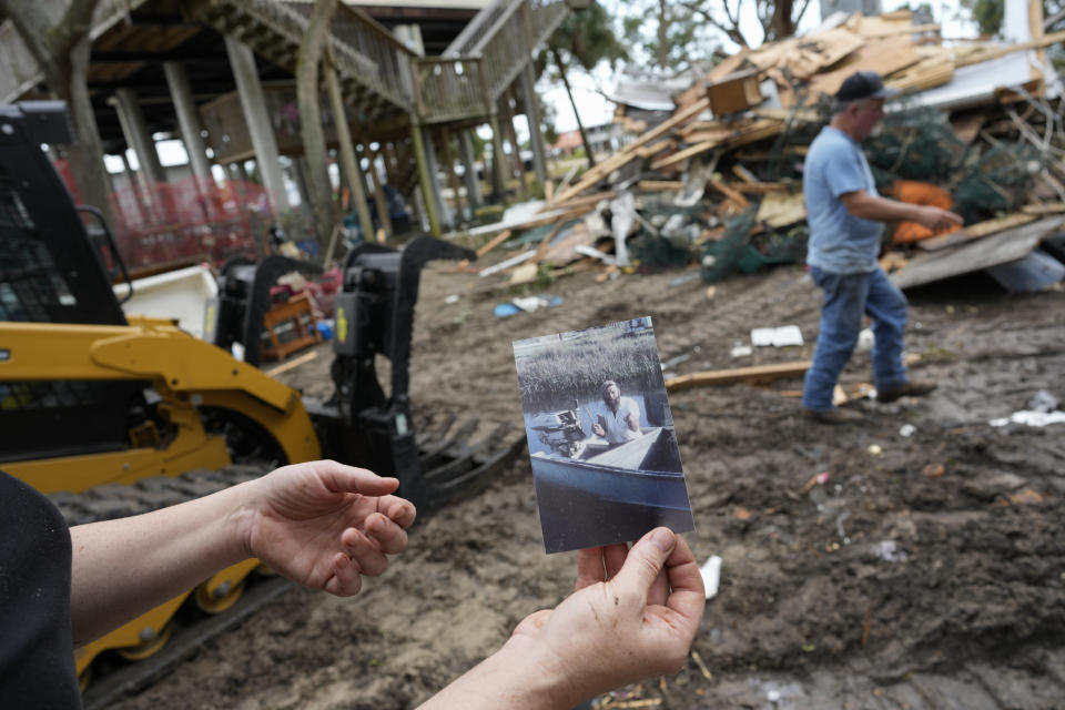 Stephanie Foley, 41, holds up a photograph of her grandfather, once the town's mayor, which she found in the wreckage of an old house which had served as a base for her father's crabbing business until being destroyed in Hurricane Idalia, in Horseshoe Beach, Fla., Friday, Sept. 1, 2023. Foley described Horseshoe Beach as a closely knit community where folks don't feel they have to lock their doors and you can go fishing anytime you want. But she fears that the traits that make the place special could vanish, with rebuilding prohibitively expensive for many of the longterm residents, and some new residents trying to change the character of the town away from one based on making a living on the water.(AP Photo/Rebecca Blackwell)