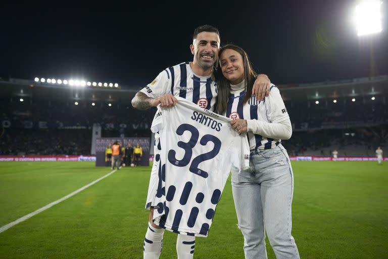 El delantero, con su pareja, muestra la camiseta de Talleres con un número simbólico