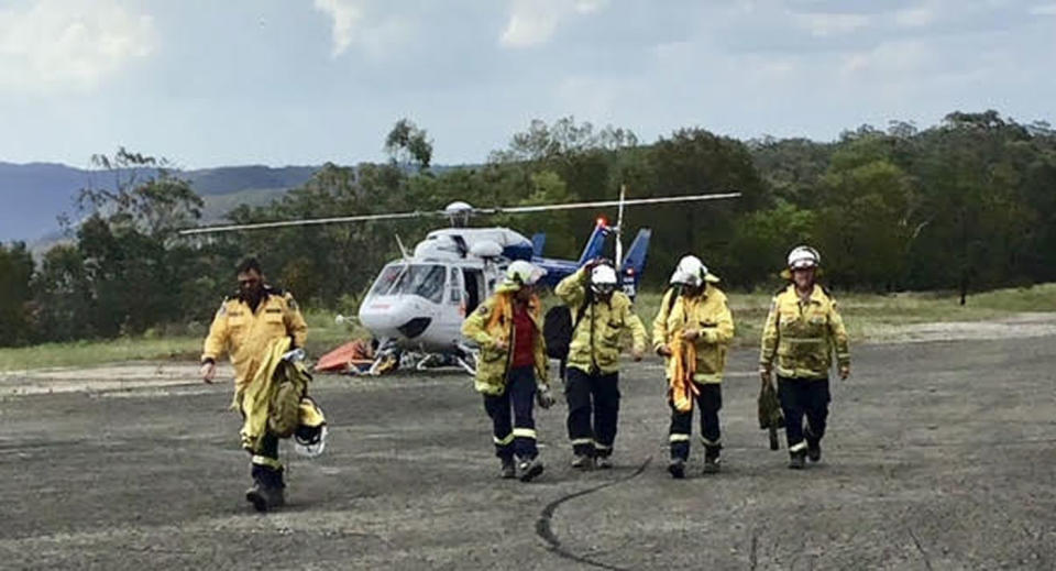 NSW Rural Fire Services firefighters are pictured next to a helicopter.